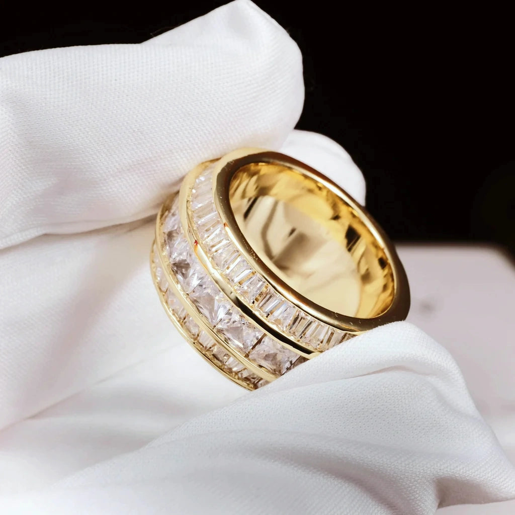 Close‑up detail shot of gold Baguette Square Triple Row Ring held with white microfiber glove, 12mm wide men hip hop band ring, hand set flawless VVS simulated baguette and square diamonds full pavé heavy weight 18k gold plated icy mens statement jewelry RDRIP JEWELRY
