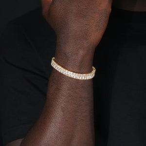 Blaze Retro Baguette‑Cut Iced Tennis Bracelet 18k gold plated worn on dark‑toned male wrist, men old‑school 90s hip‑hop bracelet, full row baguette‑cut AAA cubic zirconia stones, unisex iced‑out single row tennis chain bracelet, streetwear party hip‑hop outfit men’s statement jewelry RDRIP JEWELRY
