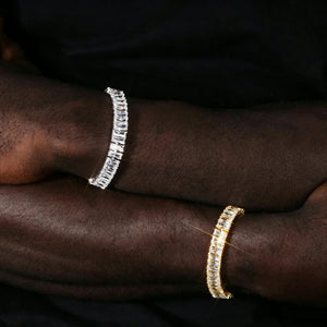 Blaze Retro Baguette‑Cut Iced Tennis Bracelet on dark skin male model wrist, men old‑school 90s hip hop jewelry, side‑by‑side silver‑toned and 18k gold plated full baguette cut AAA cubic zirconia tennis bracelet, stacked wrist shot unisex iced‑out statement bracelet for streetwear party outfit RDRIP JEWELRY
