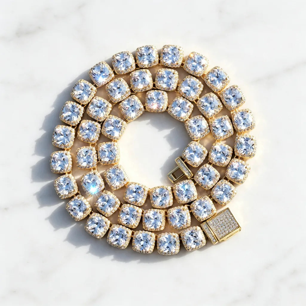 Top‑down coiled flat lay product photo of 10MM Glacier Cushion Clustered Tennis Chain in 18K Gold, featuring fully iced paved decorative clasp, flawless VVS cushion‑cut simulated cluster diamonds with bright sparkling light reflections, hand prong‑set hip hop bling necklace arranged in circular coil on clean subtle textured pure white marble surface, luxury unisex statement streetwear jewelry RDRIP JEWELRY
