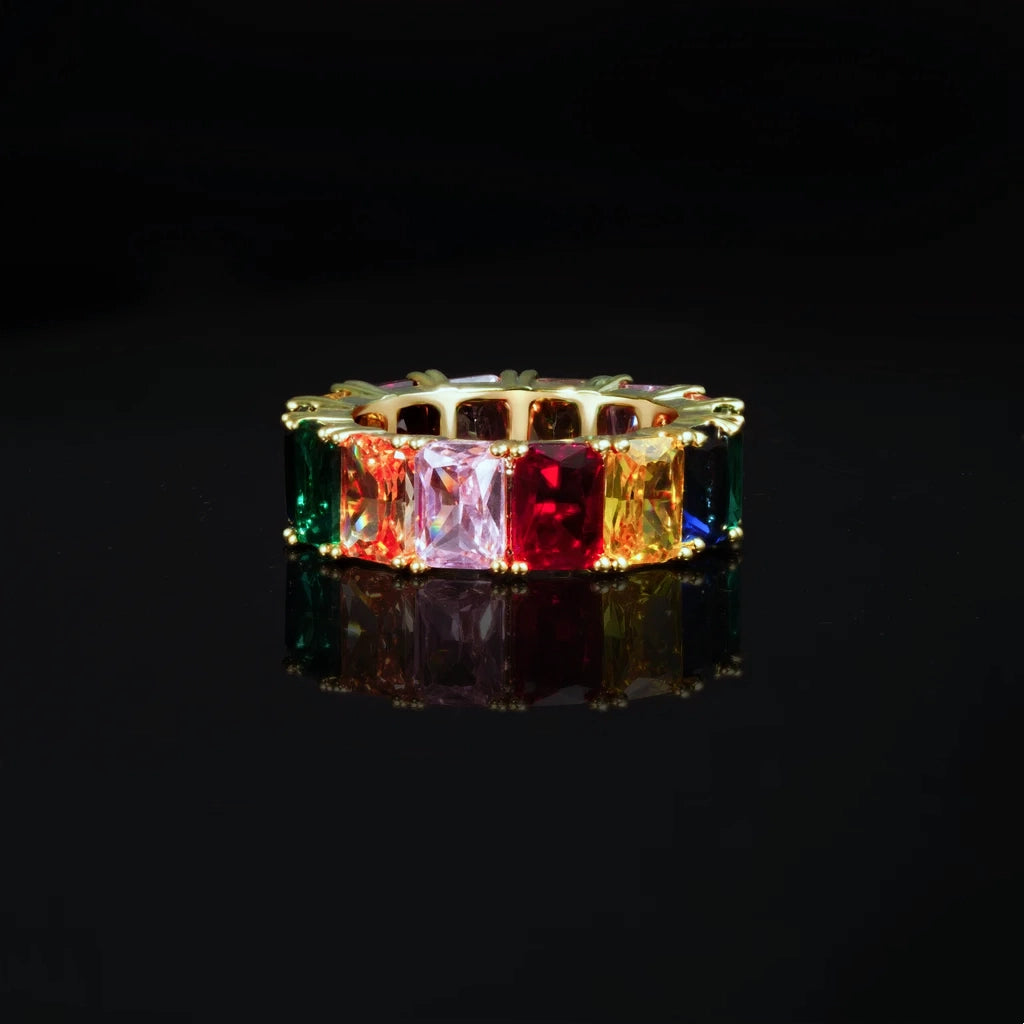 RDRIP JEWELRY Iced Out Rainbow Baguette Eternity Ring gold plated front close up product photo vivid multicolor baguette cut cubic zirconia stones prong set full band hip hop bling ring displayed on black glossy reflective surface unisex fashion statement jewelry
