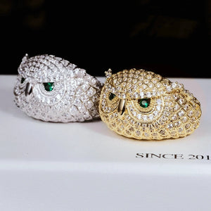 Angled product shot of Iced Owl King Ring, gold plated and white gold plated owl rings laying side by side, detailed scale texture, brilliant emerald green eyes, fully micro paved flawless VVS simulated diamonds, heavy hip hop mens statement bling jewelry RDRIP JEWELRY
