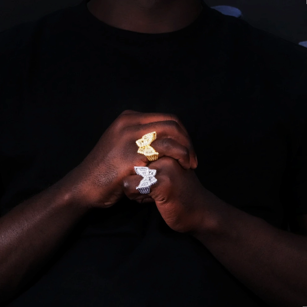 Model wearing two oversized 3D butterfly iced rings gold plated and silver finish full micro pave baguette aaa cubic zirconia mens hip hop bling jewelry lifestyle hand wear shot black outfit dark background RDRIP JEWELRY
