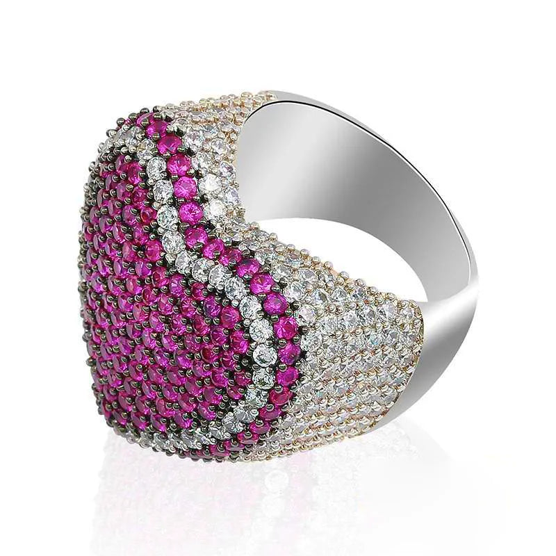 Side profile angled shot of magenta pink iced out pave love heart ring, showing polished smooth inner band, full micro hand‑set AAA cubic zirconia stones, two‑tone pink and clear CZ pave detailing, thick wide heavy‑set hip hop statement heart ring, isolated white studio background, unisex bling rapper fashion jewelry for men and women RDRIP JEWELRY
