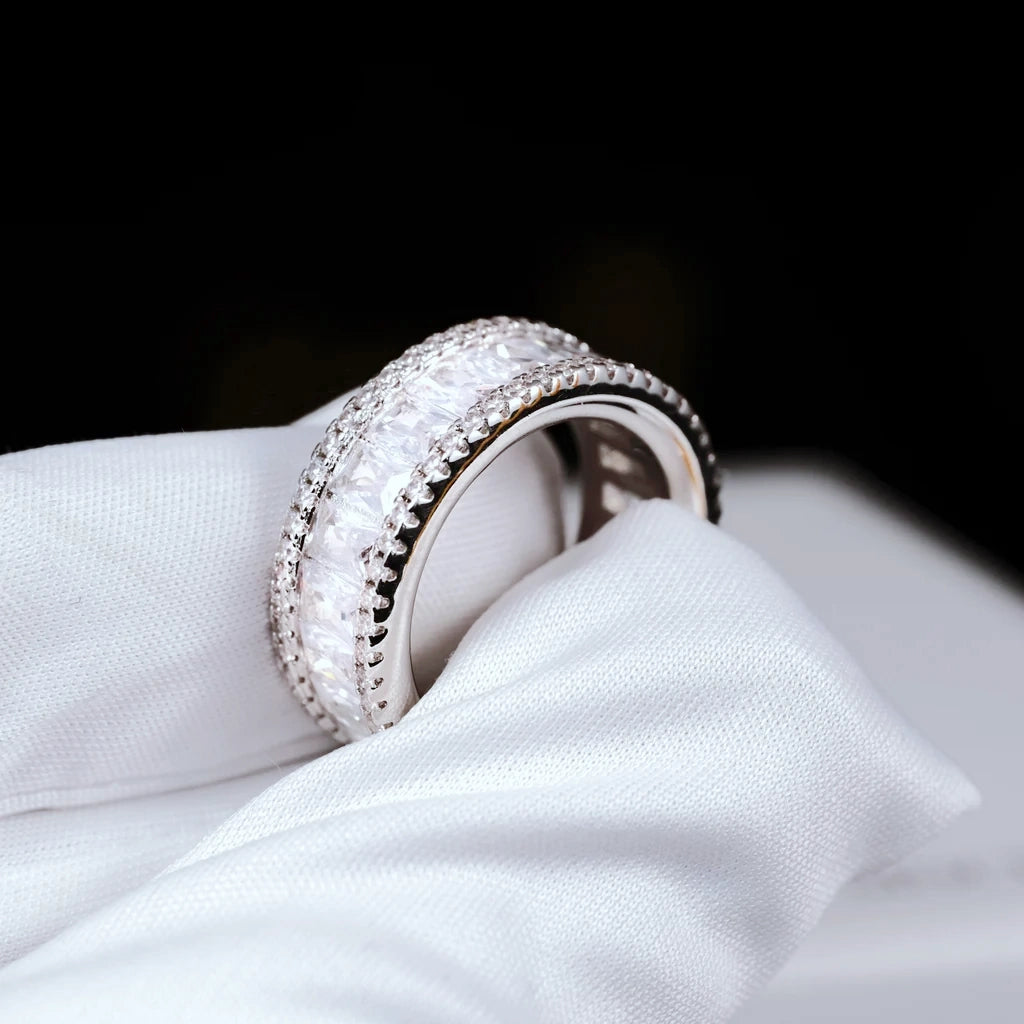 Side angle product shot of 18K gold plated wide baguette cut eternity band ring double row micro pave setting 8mm width VVS grade simulated diamonds full iced out bling hip hop mens statement ring resting on white branded jewelry box RDRIP JEWELRY
