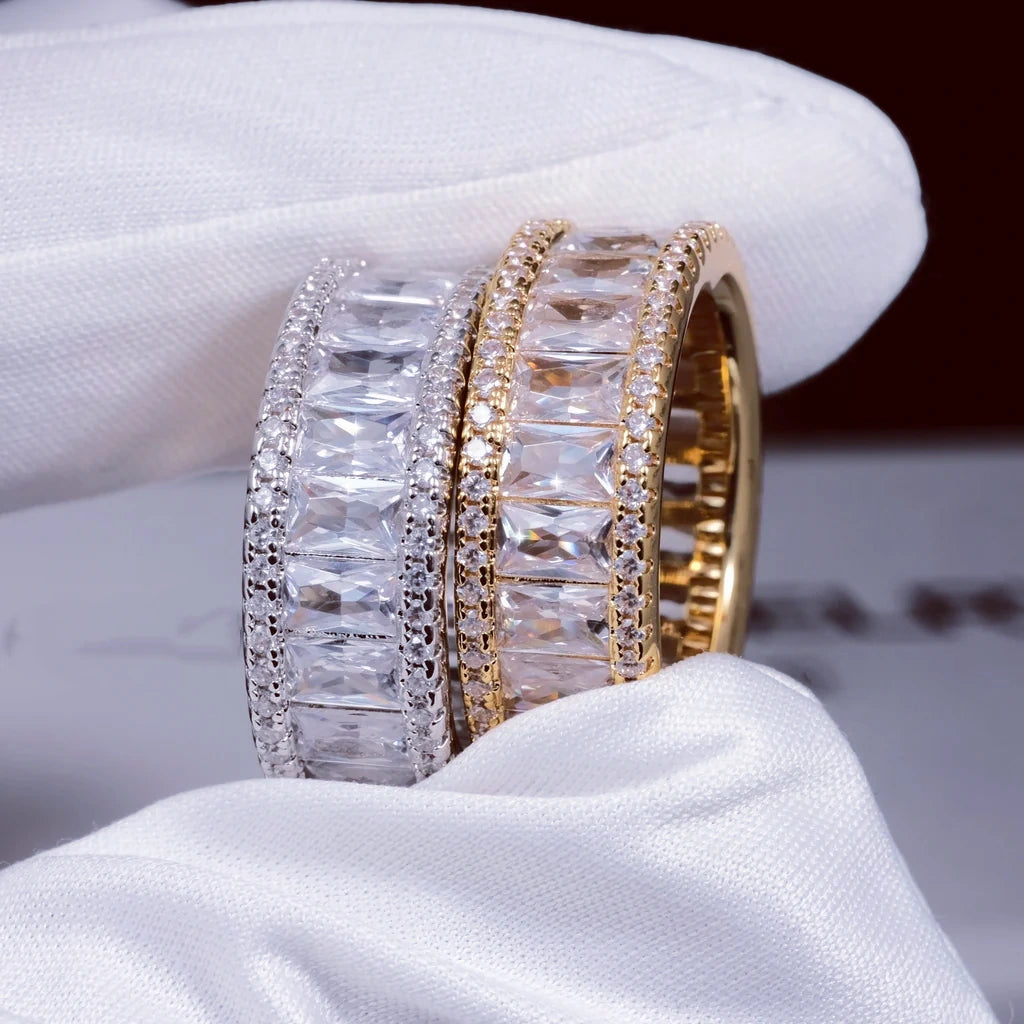Close up side view of gold and white gold plated wide baguette eternity ring double sided micro pave 8mm band flawless VVS simulated diamonds men hip hop icy bling rings held by white cotton glove showing stone details RDRIP JEWELRY
