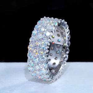 Angled side profile view of iced out 3‑row cluster eternity ring, D‑color VVS1+ hearts and arrows moissanite stones hand‑set on genuine 925 sterling silver white gold plated band, showing inner ring structure and brilliant rainbow fire sparkle, hip‑hop unisex bling statement ring displayed on clean soft white surface background, luxury men’s icy full eternity band RDRIP JEWELRY
