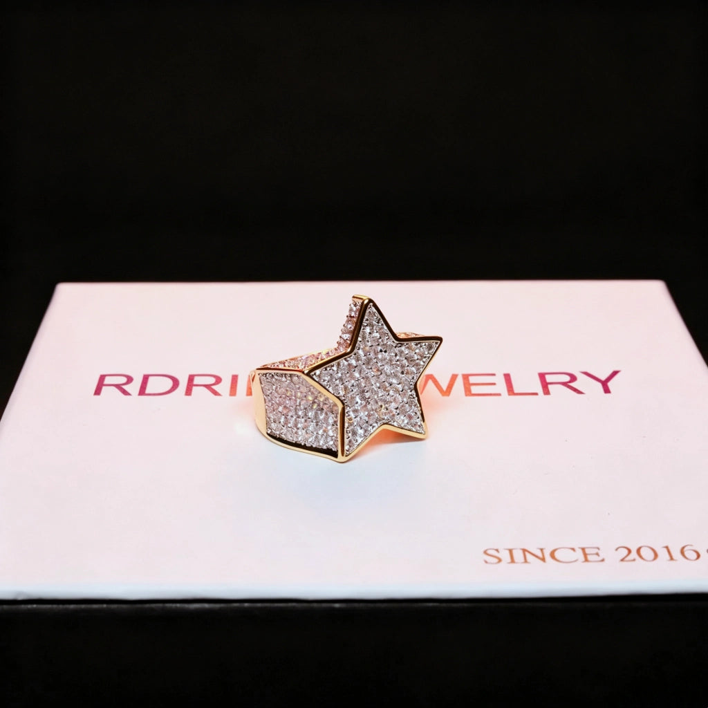 Angled product shot of gold plated iced out pentagram wide band hip hop ring with full micro paved cubic zirconia stones resting on branded gift box, 3D star icy bling men statement jewelry for streetwear and rap fashion RDRIP JEWELRY