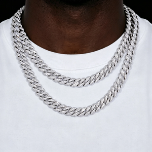 Close up shot of two layered stacked full iced out cuban link chains in 6mm and 10mm width, worn on dark deep black skin hip hop male model with plain white crew neck t-shirt, solid pure black background backdrop, fully encrusted flawless VVS grade simulated diamond stones, 18K white gold plated stainless steel heavy men statement necklace, hand prong set bling flood ice hip hop streetwear jewelry, shiny reflective diamond cuban link chain for men hip hop fashion outfit shot from RDRIP JEWELRY
