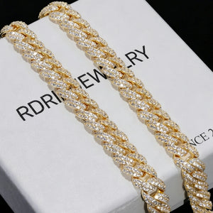 Extreme close-up shot of two 10mm full iced out gold cuban link chains fully encrusted with flawless VVS simulated diamond stones, laid on white branded jewelry box printed RDRIP JEWELRY SINCE 2016, solid pure black background, 18K gold plated heavy hip hop men statement necklace, hand prong set flood ice bling cuban chain luxury gift packaging close up display, shiny reflective diamond hip hop streetwear jewelry gift for men from RDRIP JEWELRY

