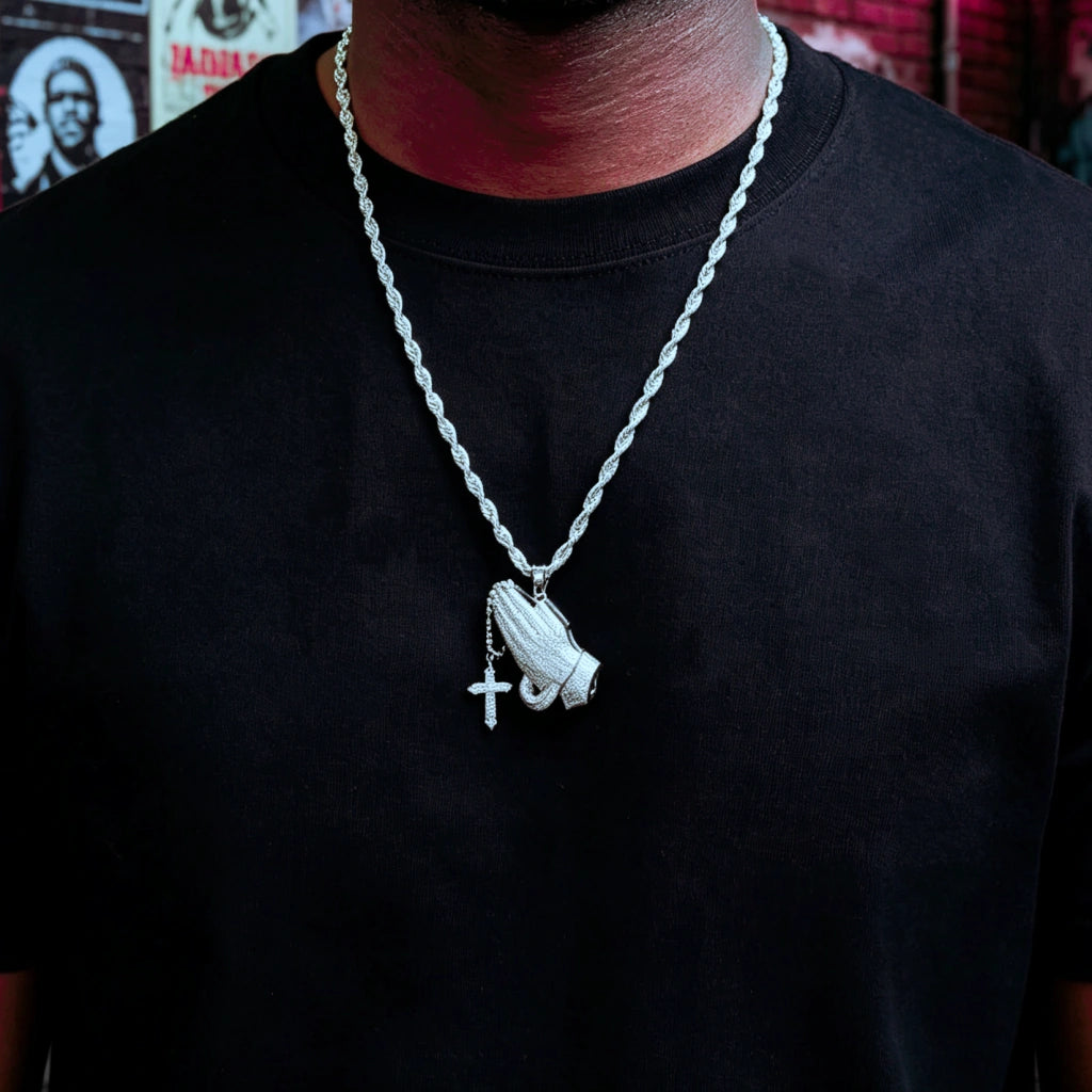 Close up view of black man wearing iced out praying hands pendant with dangling cross on twisted rope chain, s925 silver white gold plated full vvs simulated diamonds hip hop religious bling necklace urban streetwear for men RDRIP JEWELRY
