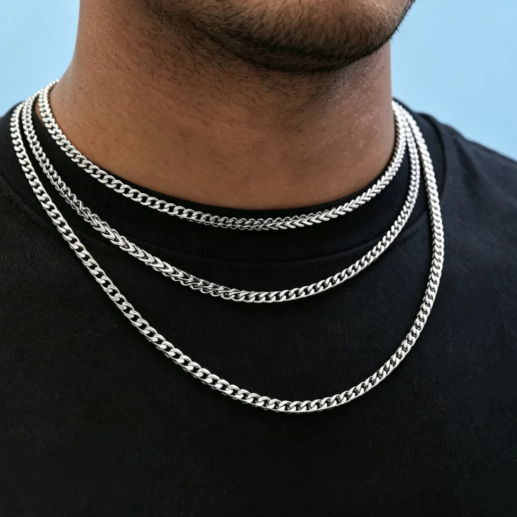 Close-up neck shot of Black male model with ultra-short stubble beard wearing three layered stackable polished 3mm white gold Italian Franco link chain necklaces, flexible tangle-resistant Franco curb chain for men hip hop streetwear fashion, premium anti-tarnish stainless steel unisex minimalist layering jewelry, sleek thin hand-finished Franco chain available in 18 inch and 20 inch lengths, lightweight shiny everyday statement necklace, can be worn alone or layered with custom hip hop pendants