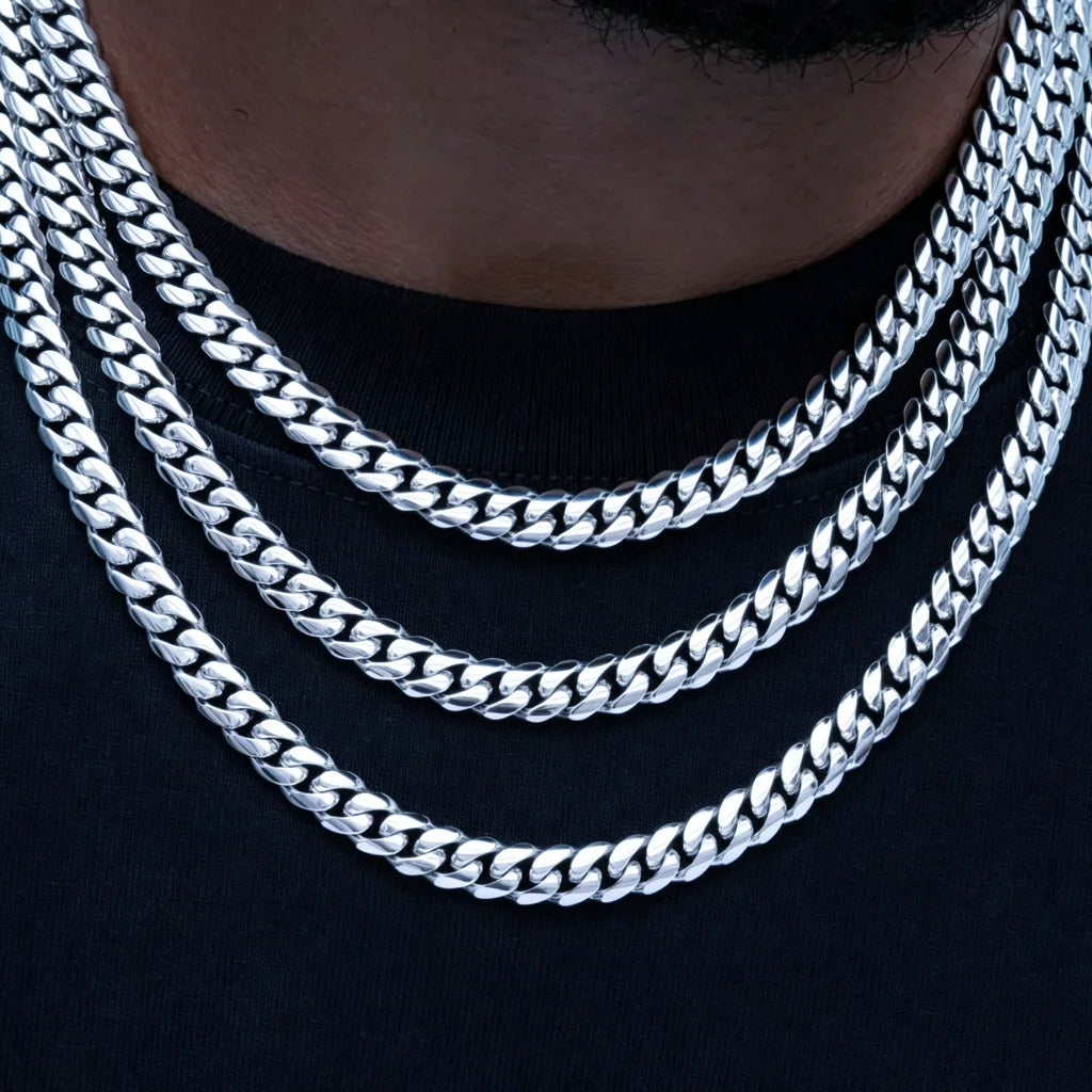 Extreme closeup shot of triple layered stackable 8mm Flagship Miami Cuban Link Chain in White Gold Tone worn on black cotton shirt, polished tight interlock stainless steel curb chain for men hip hop layered streetwear styling, anti-tarnish scratch resistant shiny icy silver finish, multiple matching lengths 16 18 20 22 24 inch, blank smooth logo-free safety clasp, durable heavy weight layering men fashion jewelry, complete gift packaging with dust pouch and lifetime warranty RDRIP JEWELRY Since 2016
