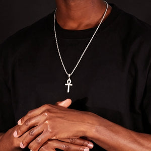 Close up shot of dark skin black male model hands crossed wearing fully iced Egyptian Ankh cross pendant on silver rope chain necklace, two tone hip hop streetwear jewelry for men against solid black background RDRIP JEWELRY
