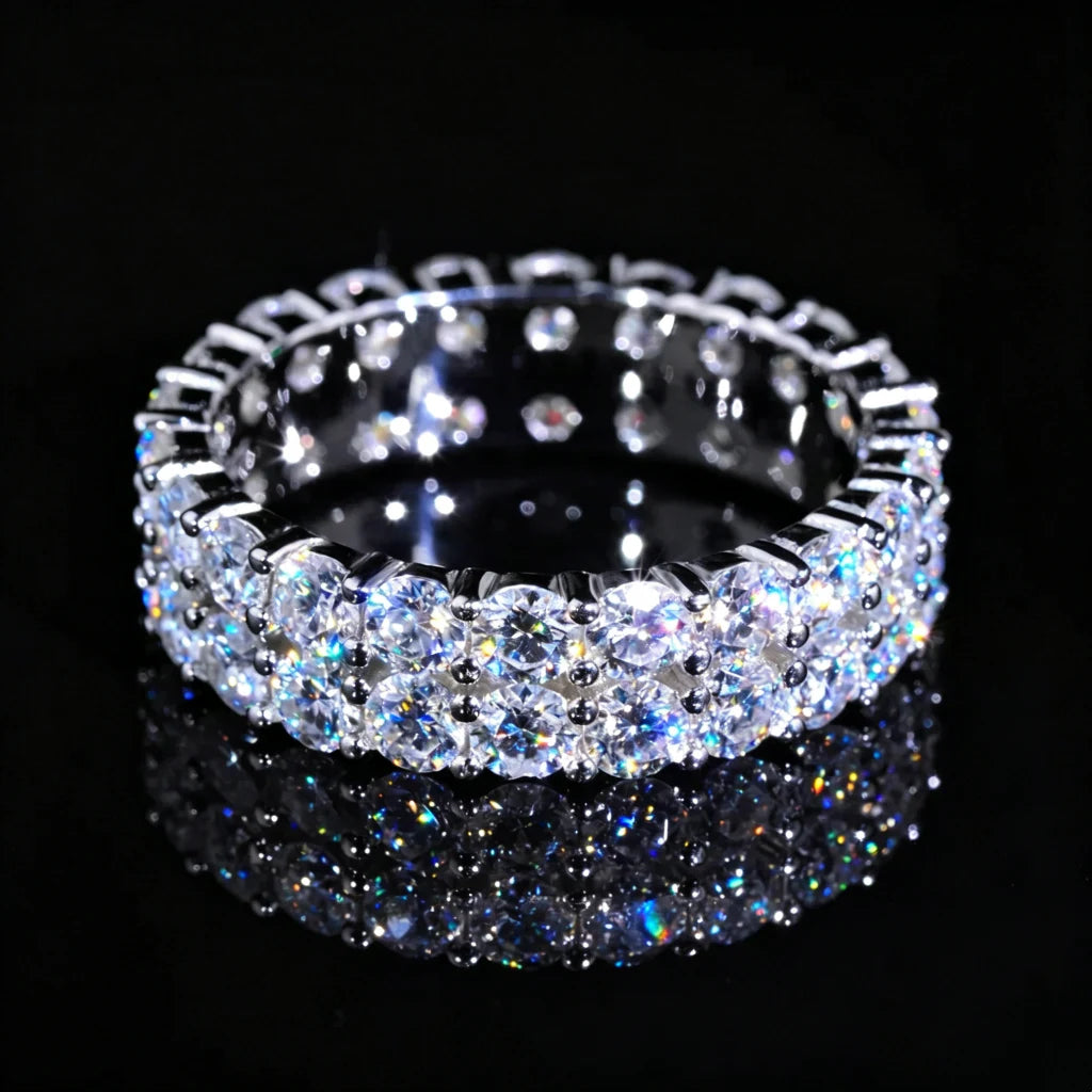 Top‑down view of 6mm double‑row full pave eternity ring, hand‑set D‑Color VVS1+ 4mm round hearts and arrows moissanite stones, genuine 925 sterling silver white gold plated icy hip‑hop unisex bling ring, vivid colorful fire and sparkle displayed on glossy black reflective surface, premium statement jewelry for men women RDRIP JEWELRY SINCE 2016

