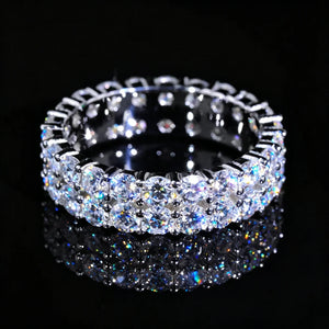 Top‑down view of 6mm double‑row full pave eternity ring, hand‑set D‑Color VVS1+ 4mm round hearts and arrows moissanite stones, genuine 925 sterling silver white gold plated icy hip‑hop unisex bling ring, vivid colorful fire and sparkle displayed on glossy black reflective surface, premium statement jewelry for men women RDRIP JEWELRY SINCE 2016
