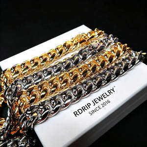 Flat lay product comparison shot of 18mm chunky Miami Cuban link chains in yellow gold plated and polished silver plated finishes, two tone heavy reflective curb chains laid on clean white branded gift box printed RDRIP JEWELRY SINCE 2016, removed diamond and globe graphic logos, solid pure black studio background, mirror polished shiny interlocking solid links, oversized hip hop statement stacking jewelry for men, anti-tarnish durable plating, luxury brand gift packaging display shot