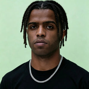 Front portrait shot of black man with dreadlocks, small eyes and neatly trimmed short beard, wearing polished 8mm Flagship Miami Cuban Link Chain in White Gold Tone, solid soft light green background, thick tight interlock stainless steel curb necklace for men hip hop streetwear, anti-tarnish no fade shiny icy finish, blank smooth safety clasp without engraved logo, available lengths 16 18 20 22 24 inch stackable everyday layering jewelry, heavy durable men fashion chain with full gift box, dust pouch and l