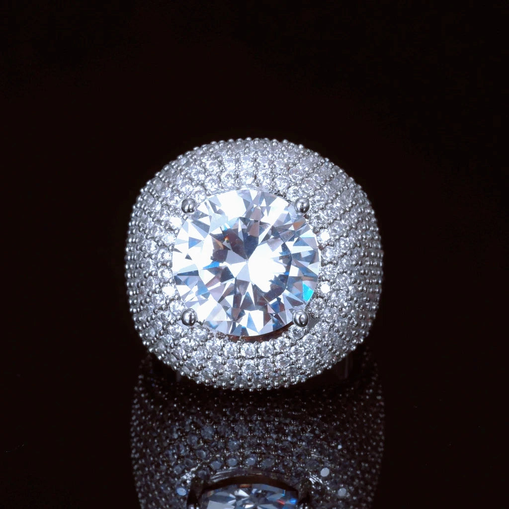 Front top‑down view of men's hip‑hop Glory Dome Iced Clustered Band Ring, huge round brilliant cut center stone secured by four prongs, full layered micro pave hand‑set VVS flawless simulated diamonds dome band, heavy 18K white gold plated bling statement mens ring, shot on dark black reflective background RDRIP JEWELRY
