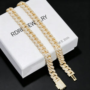 Flat lay packaging shot of 10mm full iced out gold cuban link chain covered with flawless VVS simulated diamond stones, placed on white branded jewelry box printed with RDRIP JEWELRY SINCE 2016, solid pure black smooth background, 18K gold plated heavy men hip hop statement necklace, fully hand-set prong flood ice cuban chain with fully encrusted diamond clasp, premium streetwear rap bling jewelry gift box display for men from RDRIP JEWELRY
