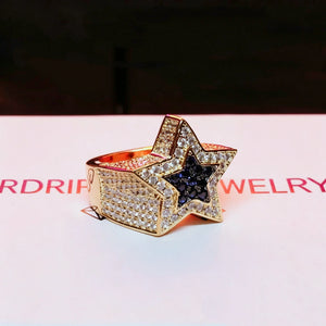 Side view shot of men's gold‑toned iced out double pentagram star hip hop ring, fully micro‑paved wide band covered with AAA white cubic zirconia stones, center inlaid deep blue CZ star, heavy‑weight statement rap jewelry for street style, premium hand‑set bling ring for men gift collection from RDRIP JEWELRY
