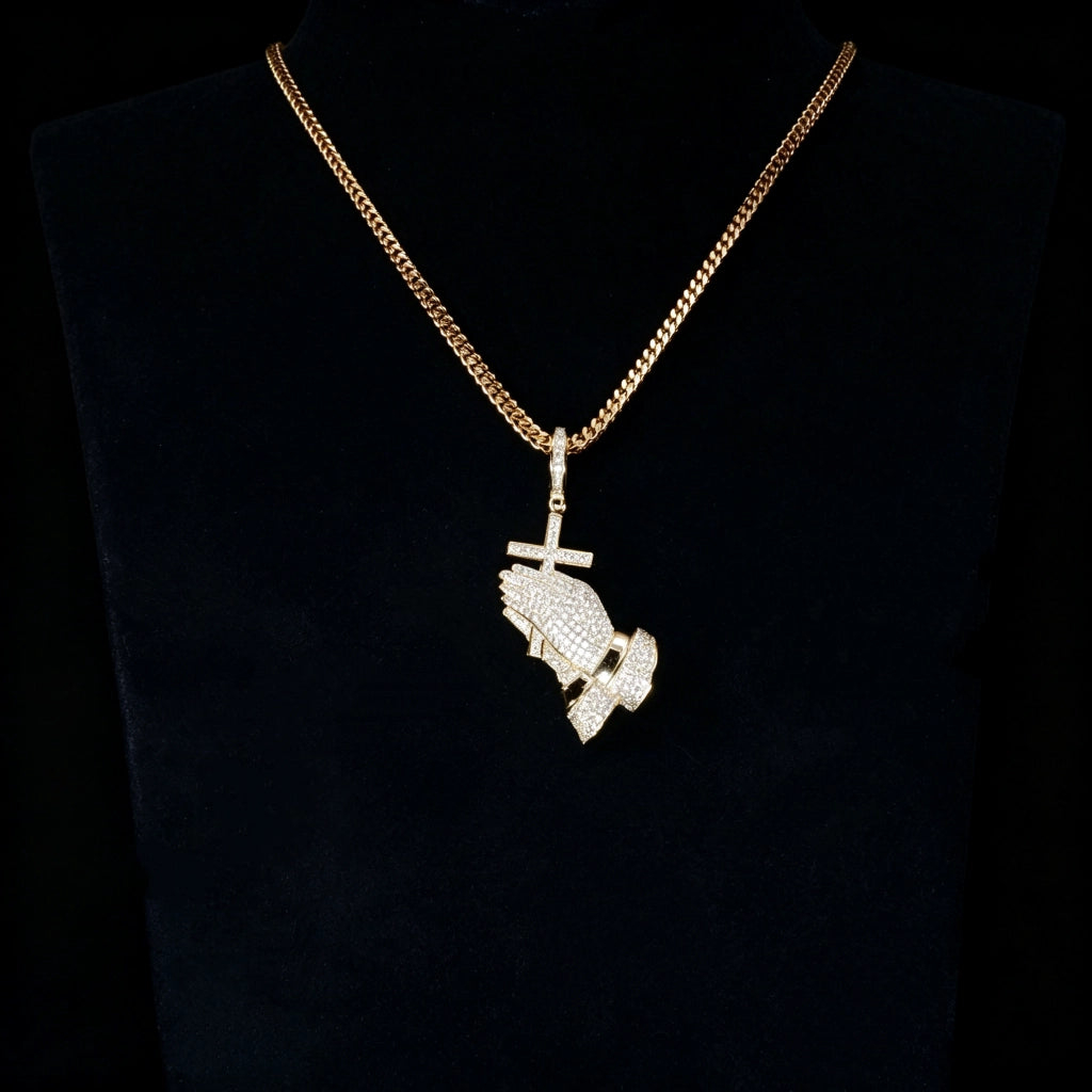 Gold iced out praying hands with cross pendant matched with gold cuban chain displayed on black mannequin bust, fully encrusted flawless vvs simulated diamonds, hip hop religious bling necklace for men dark studio display shot RDRIP JEWELRY
