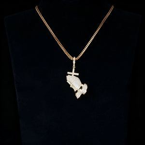 Gold iced out praying hands with cross pendant matched with gold cuban chain displayed on black mannequin bust, fully encrusted flawless vvs simulated diamonds, hip hop religious bling necklace for men dark studio display shot RDRIP JEWELRY

