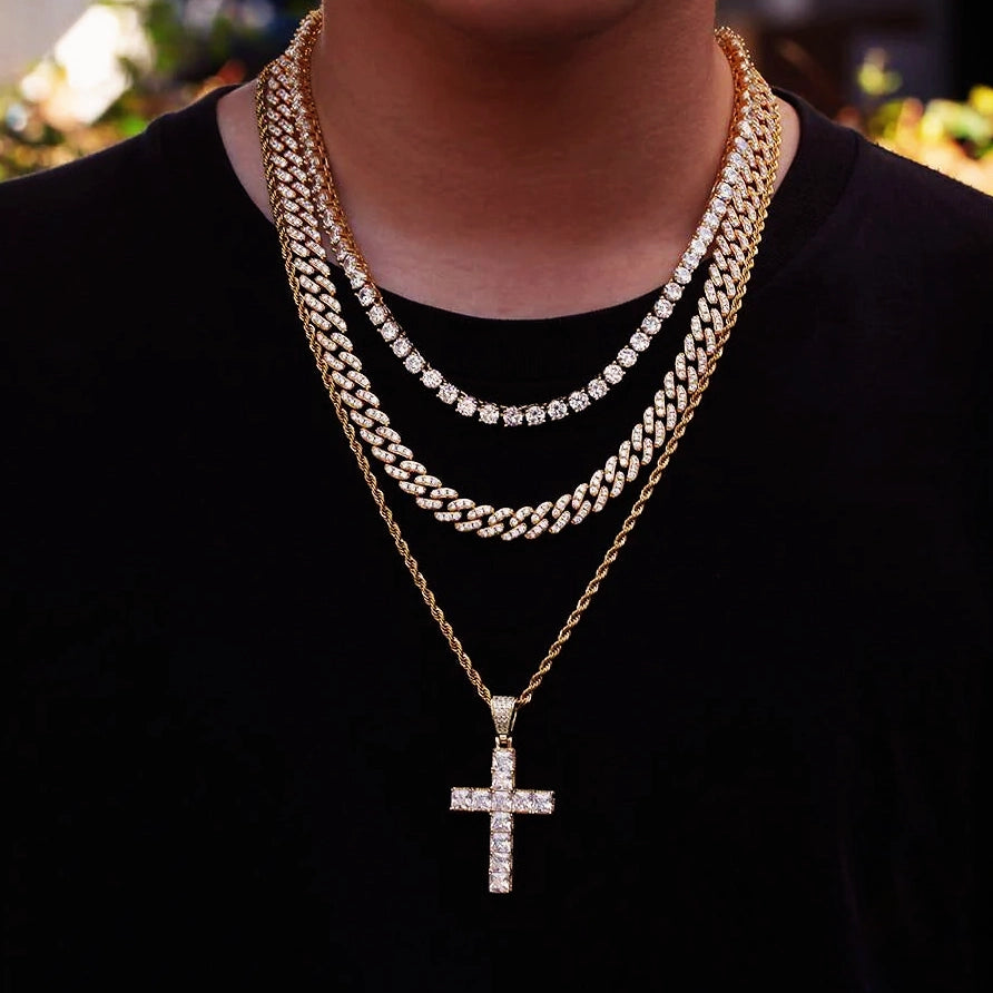 Men lifestyle outdoor shot wearing layered hip hop necklaces, 18k gold plated baguette iced cross pendant on rope chain stacked with iced tennis chain and miami cuban link chain, bling religious street fashion jewelry on black tee RDRIP JEWELRY
