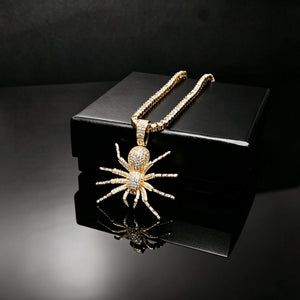 Gold plated Iced Tarantula Spider Pendant with baguette tennis chain laid on premium black gift box, full micro pave VVS simulated diamonds hip hop necklace for men, product shot on seamless black glossy reflective surface, luxury bling rap streetwear jewelry RDRIP JEWELRY
