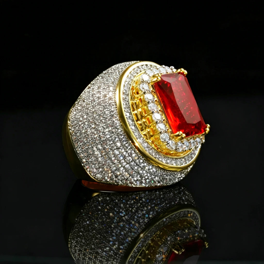 Luxury product photograph of heavy two‑tone 18k gold plated men hip‑hop champion ring, large radiant‑cut red ruby center stone secured by gold prongs, multi‑layer halo design with full micro pave hand‑set cubic zirconia stones, thick wide heavy band, brilliant icy bling shine, displayed on glossy black mirror reflective surface, dark studio background, premium rapper statement jewelry RDRIP JEWELRY
