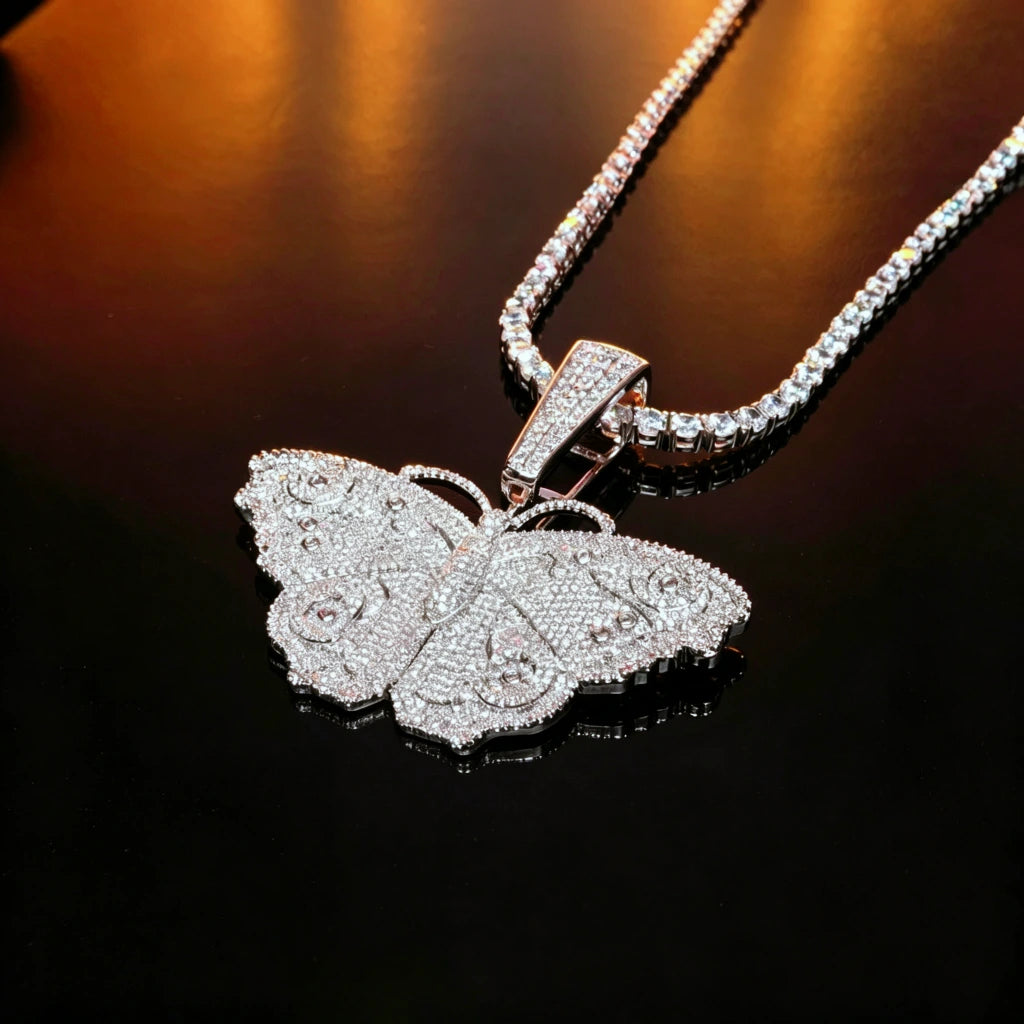 Iced Out Large Vintage Butterfly Pendant close‑up shot laid on black reflective surface, full micro pave AAA cubic zirconia hip hop bling necklace with matching tennis chain, 18k gold plated copper vintage street style jewelry for men women RDRIP JEWELRY SINCE 2016
