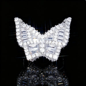 Silver finish iced out baguette butterfly ring front close‑up shot, heavy 3D hip hop men statement ring, fully hand‑set baguette cut and round cubic zirconia rhinestone stones, bright dazzling bling diamond‑simulated hip‑hop jewelry, star‑burst sparkle light effect on black reflective studio background RDRIP JEWELRY
