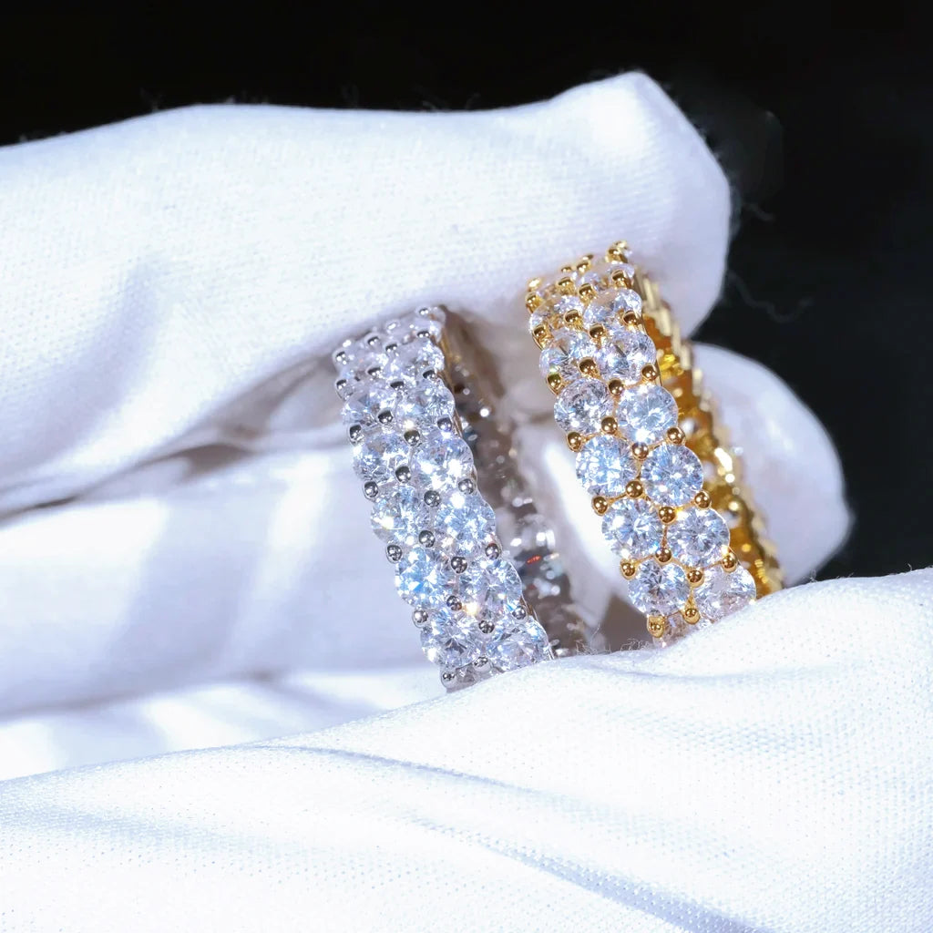 RDRIP JEWELRY iced out double row eternity band macro close‑up shot gold silver two rings held in white cotton glove prong‑set 3mm round VVS simulated diamonds full iced hip hop men stackable ring 6mm width copper base bling hiphop jewelry showing stone sparkle details dark background studio photograph
