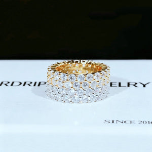 RDRIP JEWELRY iced out double row eternity band single gold tone ring placed on white branded gift box printed SINCE 2016 prong‑set 3mm round VVS simulated diamonds full iced hip hop mens wide stackable ring 6mm width copper base bling jewelry front view studio product close‑up dark blurred background
