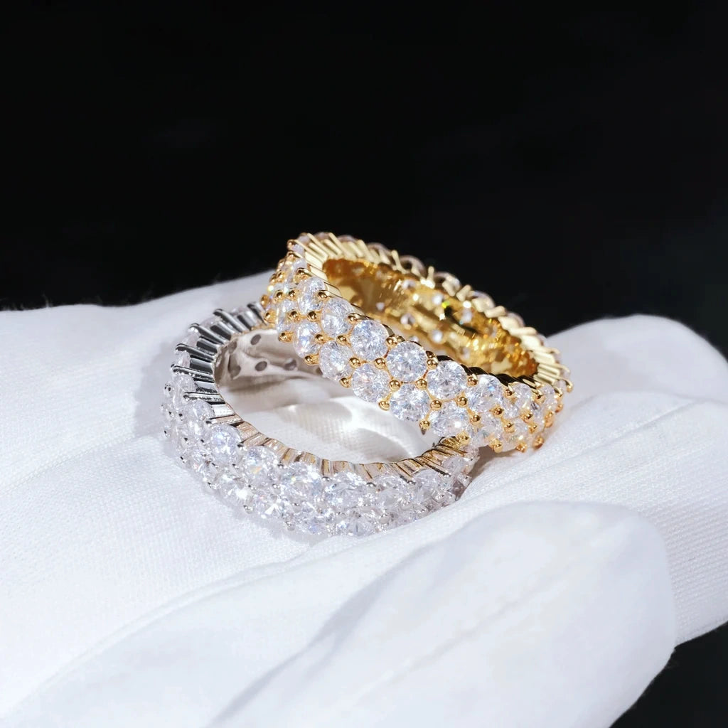 RDRIP JEWELRY iced out double row eternity band gold and silver rings held on white cotton glove prong set 3mm VVS simulated diamonds full iced hip hop mens stackable ring 6mm width copper base bling hiphop jewelry close up studio product photograph
