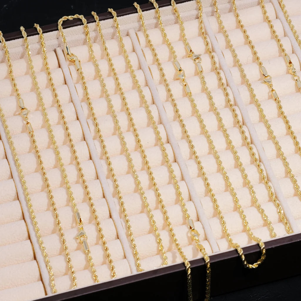 Flat lay studio product shot of bulk 2mm 18k gold plated twisted rope chains neatly arranged inside beige divided velvet jewelry display tray, assorted available lengths 18 inch 20 inch 24 inch slim dainty twist link necklaces, unisex stackable hip hop staple chain blanks perfect for matching custom pendants, hand polished anti-tarnish gold rope chain wholesale stock photography, fine minimalist men streetwear jewelry supply RDRIP JEWELRY 
