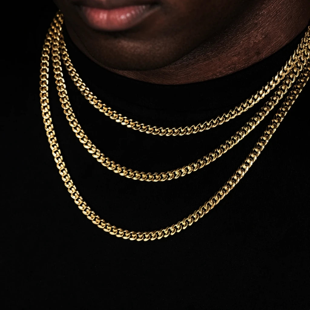 Extreme close-up shot focusing on male lips and neck area, Black male model with ultra-short trimmed stubble beard wearing three layered stackable 5mm Miami Cuban Link Chain in polished 18k gold plated finish, sleek glossy gold cuban link necklace for men hip hop streetwear, flexible tangle-resistant link structure, available lengths 18 inch, 20 inch, 24 inch, 30 inch with weight ranging from 24 grams to 38 grams and ±5 gram weight tolerance, fade-resistant anti-tarnish 18k gold plating, versatile layering