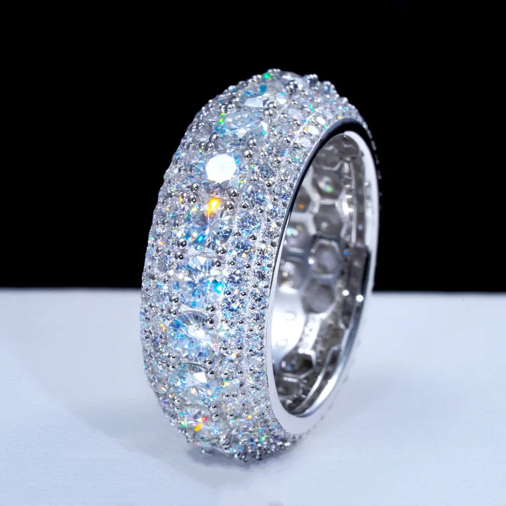 Angled side close‑up studio shot of multi‑layer pave full iced‑out men’s eternity band ring resting on clean matte white surface, hand‑set brilliant VVS1 D‑color hearts and arrows round moissanite stones, heavy 9mm width S925 sterling silver white gold plated hip‑hop ring, show detailed honeycomb hollow inner band structure, stunning rainbow fire sparkle and brilliant light refraction, luxury bling statement jewelry for men street fashion and hip‑hop culture, RDRIP JEWELRY
