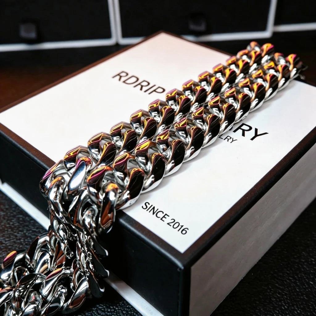Flat lay product shot of polished silver 18mm chunky Miami Cuban link chain resting on custom white branded gift box printed with RDRIP JEWELRY SINCE 2016, mirror high polish reflective curb chain links, heavy solid interlocking hip hop jewelry, luxury presentation gift box for men streetwear accessories, anti-tarnish silver plated oversized Cuban choker stacking necklace, premium hip-hop statement jewelry packaging closeup detail shot RDRIP JEWELRY since 2016
