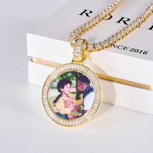 Baguette Iced Out Round Custom Photo Pendant Necklace, yellow gold tone medallion with baguette-cut stone frame, custom father and child portrait photo with glass cover reflection, tennis chain laid on RDRIP branded white gift box, light background studio shot, personalized hip hop memory jewelry, RDRIP JEWELRY
