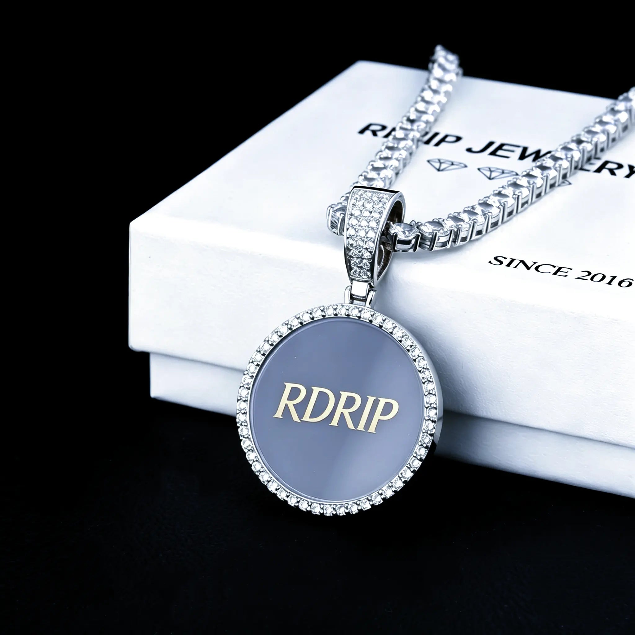 Classic Iced Out Circle Custom Photo Pendant Necklace, silver tone blank sample pendant engraved with RDRIP logo, paired with tennis chain, displayed on RDRIP branded white gift box, solid black background studio shot, personalized hip hop custom memory jewelry, RDRIP JEWELRY
