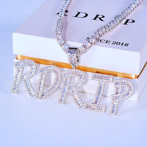Iced Out Baguette Custom Name Letter Pendant Necklace, white gold tone front view, mixed baguette and round cut stones custom letter pendant spelling RDRIP, tennis chain displayed on official RDRIP branded gift box, light background studio shot, personalized hip hop custom name jewelry, RDRIP JEWELRY

