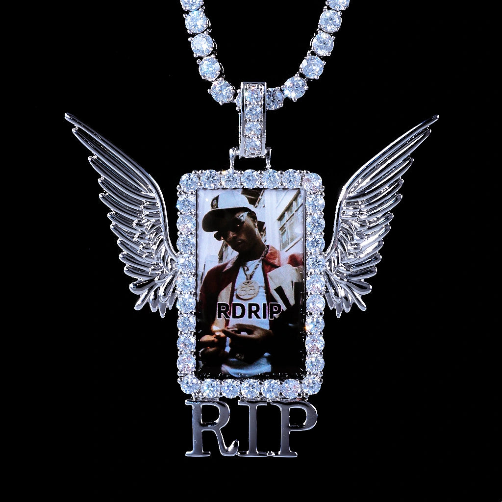 Iced Out Wings RIP Custom Photo Pendant, white gold tone hanging front view, angel wing rectangular photo frame pendant with RIP detail, encrusted round stones, matched tennis chain, solid black background, memorial personalized hip hop keepsake jewelry, RDRIP JEWELRY

