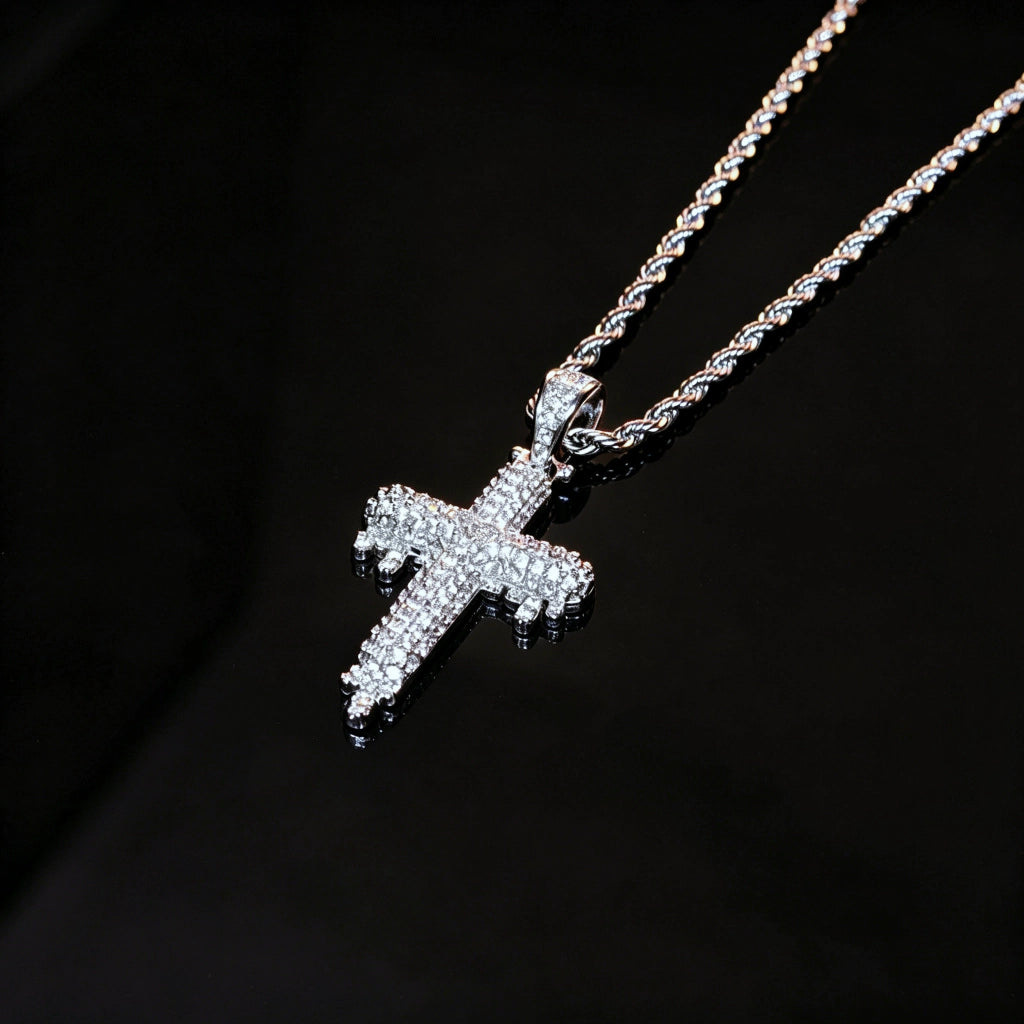 RDRIP JEWELRY SINCE 2016 Close‑up shot of Iced Out Dripping Cross Pendant on black reflective surface, fully micro paved cubic zirconia melting drip cross hip hop necklace, silver twisted rope chain, premium iced streetwear jewelry for men, brilliant sparkling stones detail view
