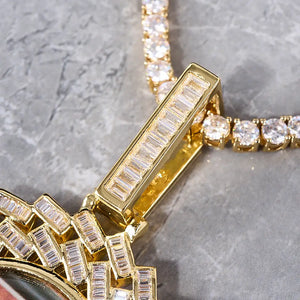 Large 3D Baguette Sunburst Custom Photo Pendant Necklace, close-up macro shot of gold baguette stone pendant bail, partial view of iced out medallion and round stone tennis chain, gray marble texture background, RDRIP JEWELRY
