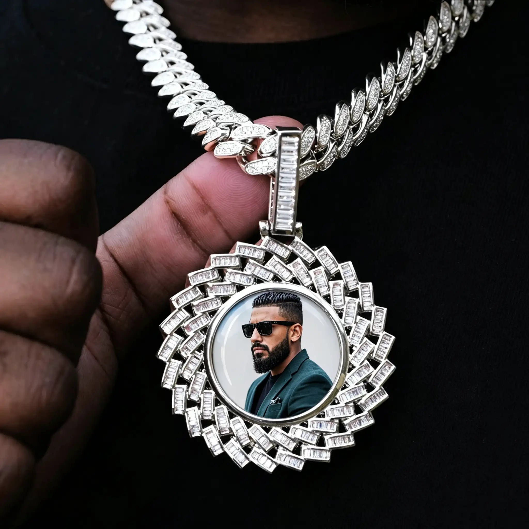 Large 3D Baguette Sunburst Custom Photo Pendant Necklace, silver tone iced out personalized photo medallion held in hand, custom portrait picture inside pendant, matched with diamond cuban chain, black fabric background lifestyle shot, RDRIP JEWELRY
