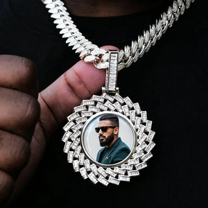 Large 3D Baguette Sunburst Custom Photo Pendant Necklace, silver tone iced out personalized photo medallion held in hand, custom portrait picture inside pendant, matched with diamond cuban chain, black fabric background lifestyle shot, RDRIP JEWELRY
