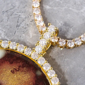 VVS MOISSANITE LARGE 3D CIRCLE CUSTOM PICTURE PENDANT, close up detail of gold tone stone encrusted bail and diamond frame, paired with matching tennis chain, grey marble texture background, RDRIP JEWELRY
