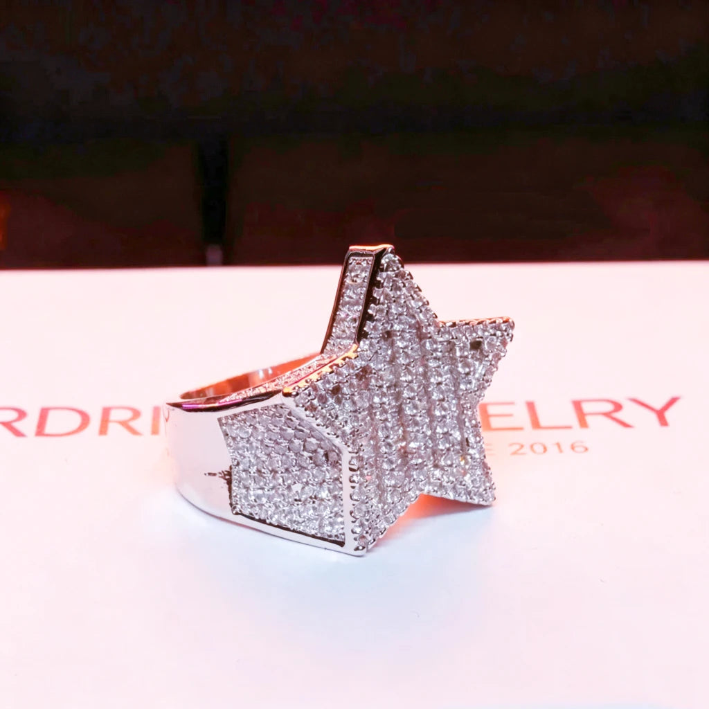 Side profile angled view of men’s heavy 3D micro‑pave pentagram star iced out ring, silver‑toned 18k gold plated finish, hand‑set mixed baguette and round cut AAA cubic zirconia stones, bulky hip‑hop rapper statement ring, displayed on branded RDRIP JEWELRY paper backdrop, urban fashion bling men jewelry, RDRIP JEWELRY
