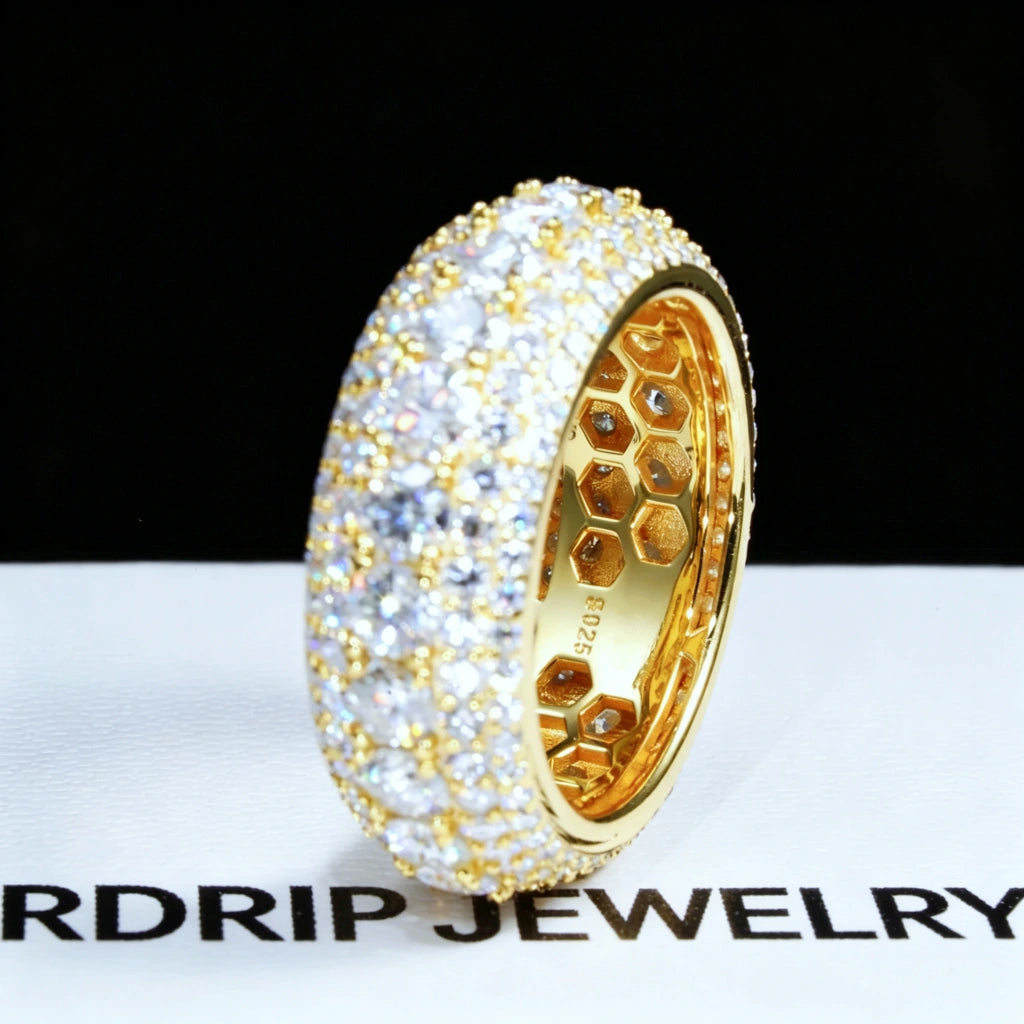 Side profile close‑up shot of men’s 9mm wide iced‑out multi‑layer full pave moissanite eternity band RDRIP JEWELRY SINCE 2016, 18K gold plated solid 925 sterling silver ring hand‑set with D‑Color VVS1 4mm hearts and arrows round moissanite stones, inner honeycomb hollow construction with S925 stamp, ring placed on branded RDRIP JEWELRY white paper surface against dark black background, premium hip‑hop bling men’s statement jewelry
